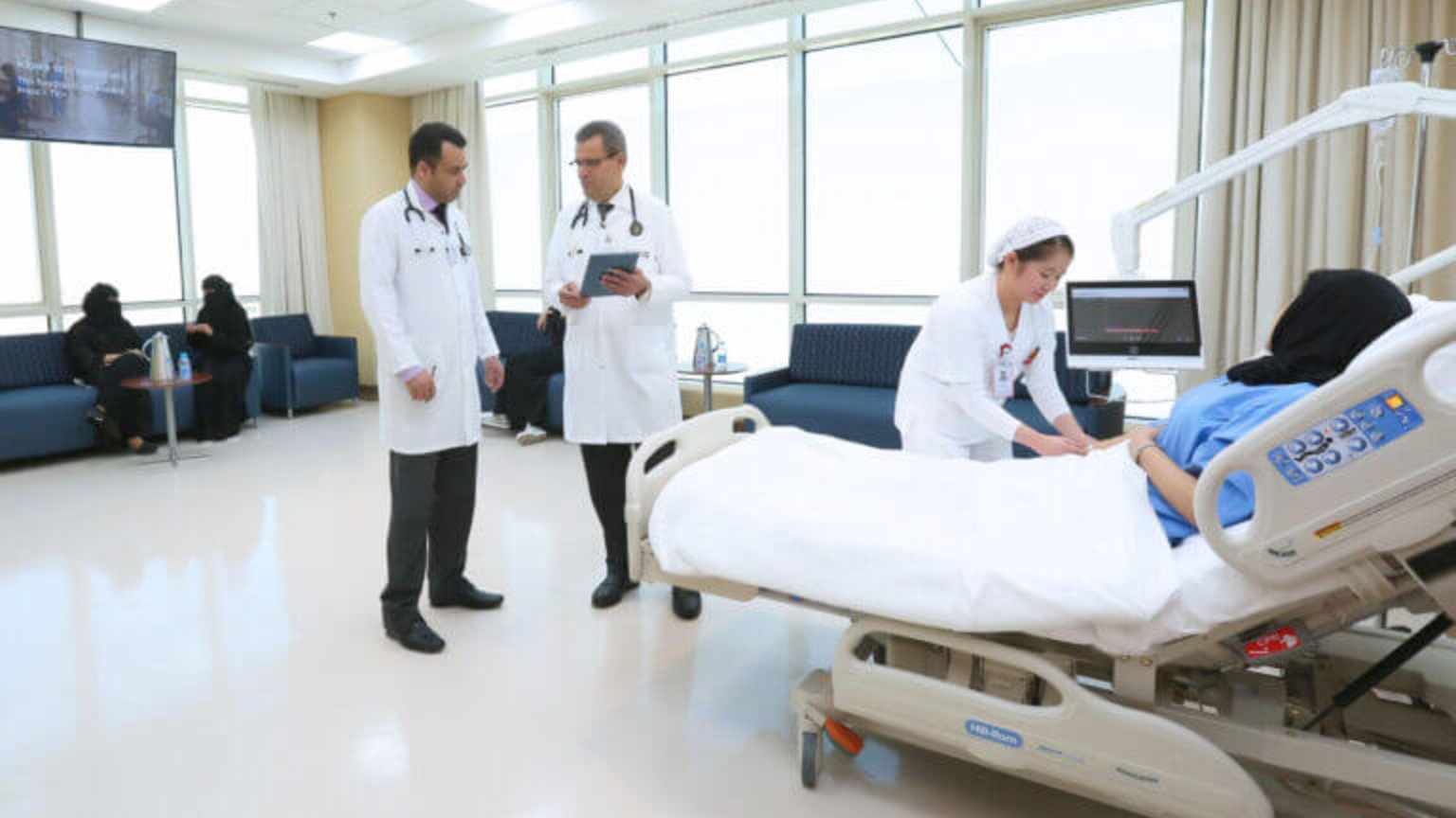 Clinicians reviewing a monitored patient bed on the ward