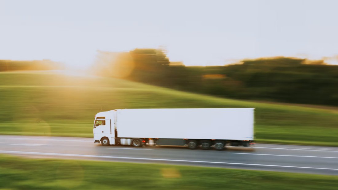 Refrigerated trailer moving along a highway at sunset