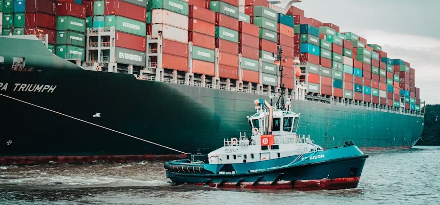 Tug guiding a loaded container vessel into port